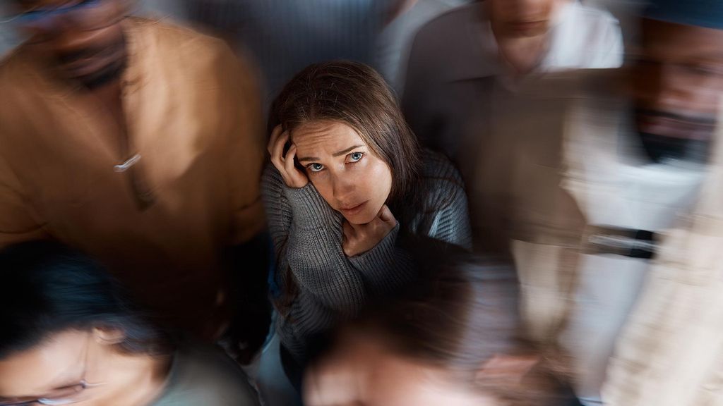 a young woman sitting on the floor with people around her.